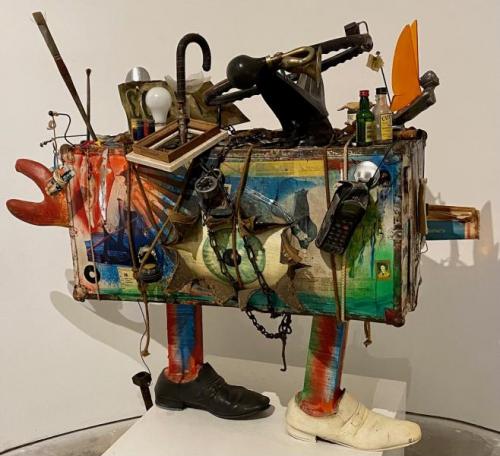 “Quest,” 1983 Acrylic on Suitcase with Frying Pan, Shoes, Glass, Glass Bottles, Orange Peel, Name Tag, Credit Card, Chain, Rope, Steering Wheel, Wood, Newspaper, Keys, Harmonica, Toothbrush, and other Mixed Media, 39 x 40 x 25 Inches